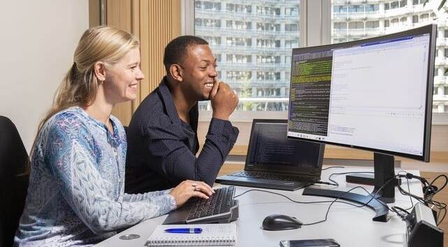 afbeelding werkende vrouw en man achter computerscherm