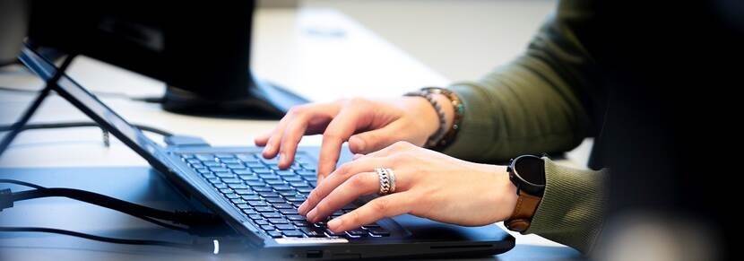 Twee handen die werken op een laptop