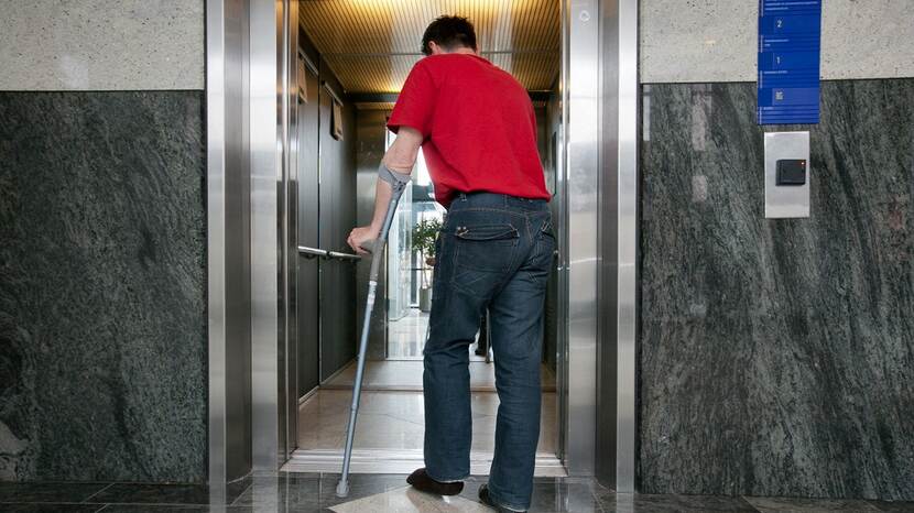 Man met loopkrukken op kantoor